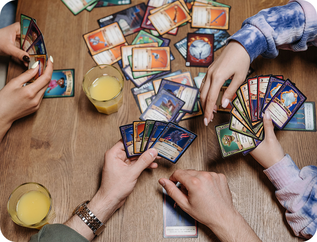 Overhead view of friends trading and playing cards around a table