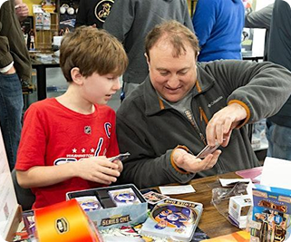 A parent and child looking through cards together at a vendor stand